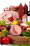 A composition of meat and vegetables with a bottle of wine isolated on white