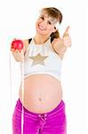 Smiling pregnant woman with measure tape and apple showing thumbs up gesture