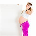 Smiling beautiful pregnant woman holding blank billboard and showing thumbs up gesture isolated on white