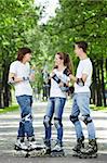 Three young skaters are drinking water in the park