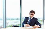 A man in business suit signs documents in the office