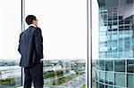 Businessman looking out of his office on the opposite building