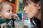 Mother and baby son using curly straws