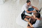 Men using laptops in living room