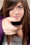 Young woman with remote control sitting on sofa close-up focused on face.