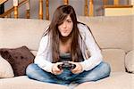 Young female concentrating playing videogames on sofa at home