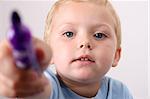 Toddler pointing his purple pen towards the camera