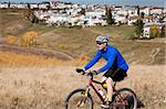 Man riding mountain bike in park near a residential area.
