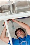 plumber making efforts to repair a sink lying on the floor in the kitchen