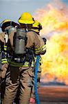 Firefighters prepare to attack a propane fire training prop.