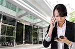 Anxious business woman phone someone and reading SMS outside of office.