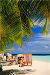 Relaxing on tropical paradise with white sand at Maldives and green palms with blue sky