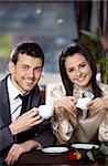 Happy sourire couple au café avec des coupes dans les mains