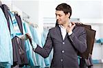 The young man chooses clothes in shop