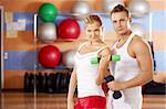 Pair of sportsmen with dumbbells in hands in sports club