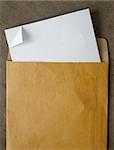 White paper from a brown open envelope on wood table