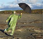 The comical person in protective scientific overalls with an umbrella in a hand