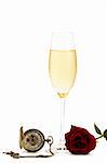 cold glass with champagne with a red rose and a old pocket watch on white background