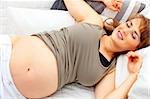 Smiling beautiful pregnant woman relaxing on sofa at home.