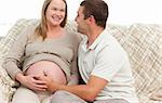 Happy man touching the belly of his pregnant wife while looking at each other