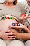 Close up of future parents holding cubes forming the words mom ,dad and baby