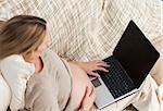 Top view of a future mom using her laptop on the sofa at home