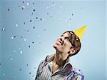 caucasian woman looking at confetti in the air. Horizontal shape, side view, head and shoulders, copy space