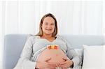 Portrait of a pregnant woman having mom letters on her belly at home