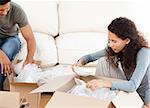 Happy woman packing glasses with her husband in the living-room for their removal