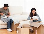 Joyful couple packing glasses together in the living room for their new house
