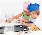 Two adorable children making biscuits together in the kitchen