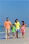 A happy family of mother, father and two children, son and daughter, walking and having fun in the sand of a sunny beach