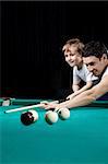 The young man and the little boy play billiards