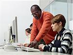 Computer class with indian male teacher helping female student. Horizontal shape, side view, waist up, copy space