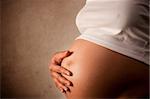 Pregnant woman holding her belly  over dark background