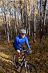 Middle-aged man mountain biking on forest trail
