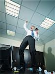 mature business man standing on desk and screaming for joy. Vertical shape, full length, copy space