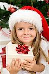 Adorable little girl holding present wearing a christmas hat - closeup