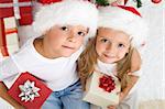 Lovely kids at christmas time with santa hats and presents