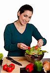 Beautiful woman preparing a delicious organic salad with lettuce, tomato, bell peppers and onion in kitchen, isolated.