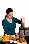Beautiful woman in kitchen making fresh squeezed organic juice using a juicer, isolated.