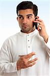 Ethnic mixed race businessman wearing traditional robe is using a mobile phone and looking sideways.