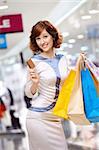 Young beautiful woman smiles in shop with bags and a credit card