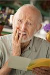 Senior man at home reading sympathy card