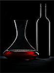 Red wine, bottle and decanter silhouette over black background