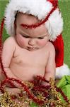 Christmas Baby playing with decorations on a green background