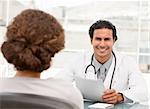 Cheerful hispanic doctor dring an appointment with a patient at the hospital