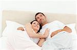 Relaxed couple lying together on their bed in the morning at home