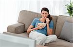 Attractive woman watching television and eating pop corn on the sofa at home