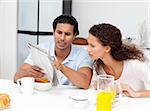 Serious man showing the newspaper to his wife during breakfast at home